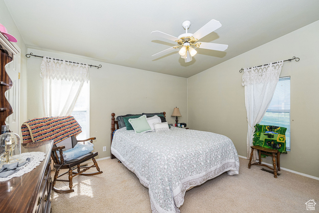 Bedroom featuring light colored carpet, ceiling fan, baseboards, and lofted ceiling