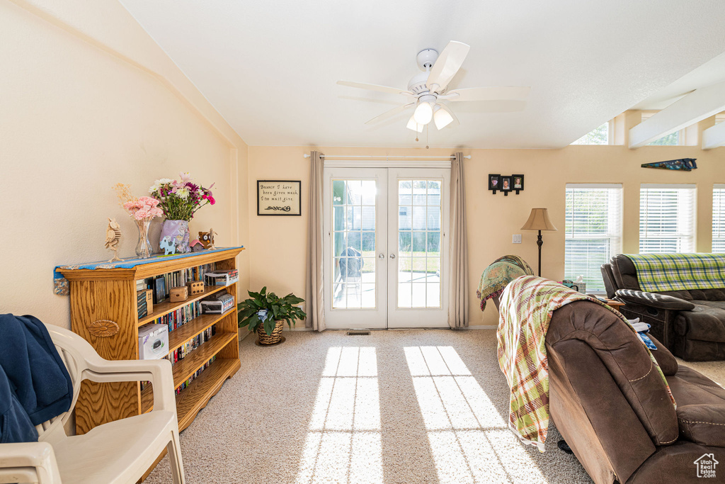 Carpeted living area with french doors and ceiling fan