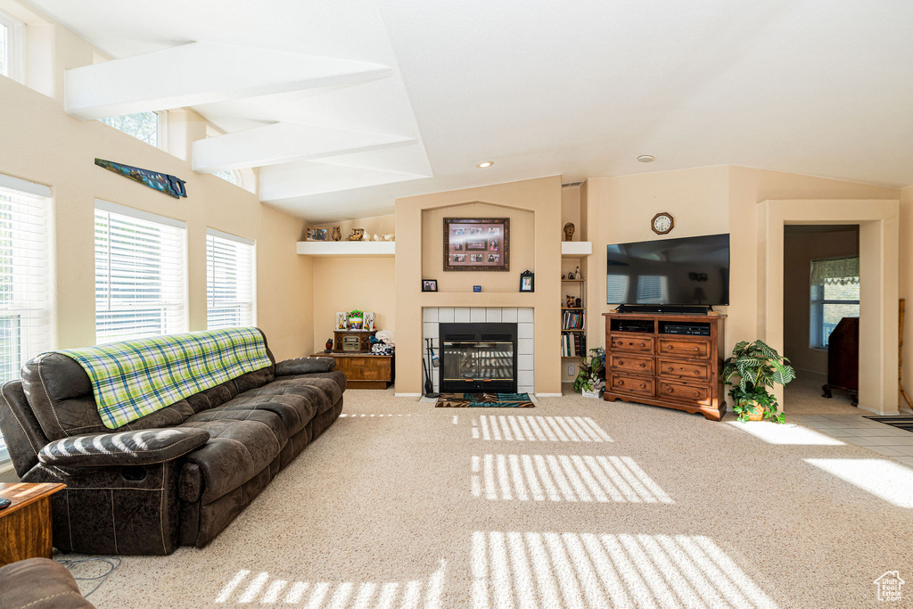Carpeted living room with healthy amount of natural light, a tile fireplace, and lofted ceiling