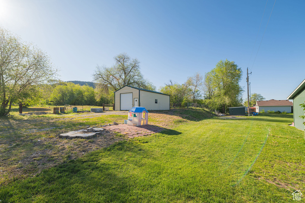View of green lawn featuring an outbuilding and a garage