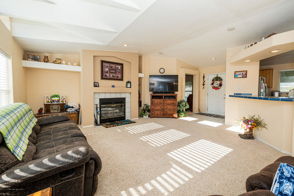 Living room with carpet floors, a fireplace, lofted ceiling, and recessed lighting