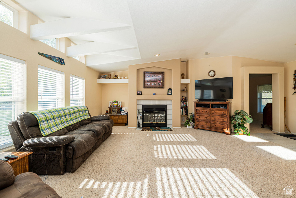 Carpeted living area featuring vaulted ceiling and a tile fireplace