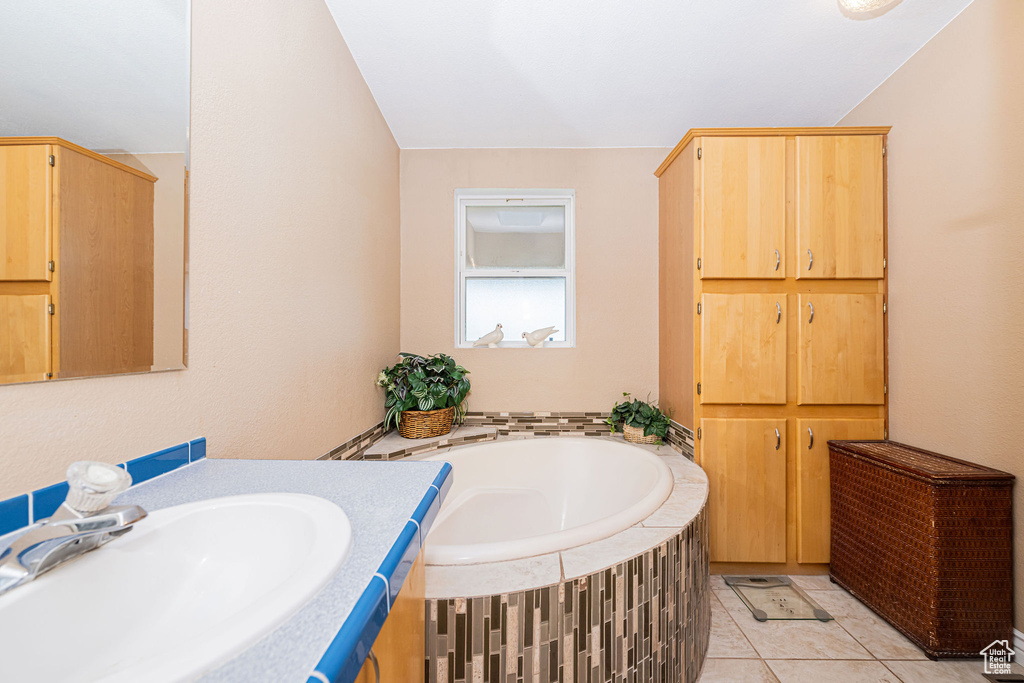 Bathroom with a garden tub, vanity, and tile patterned flooring