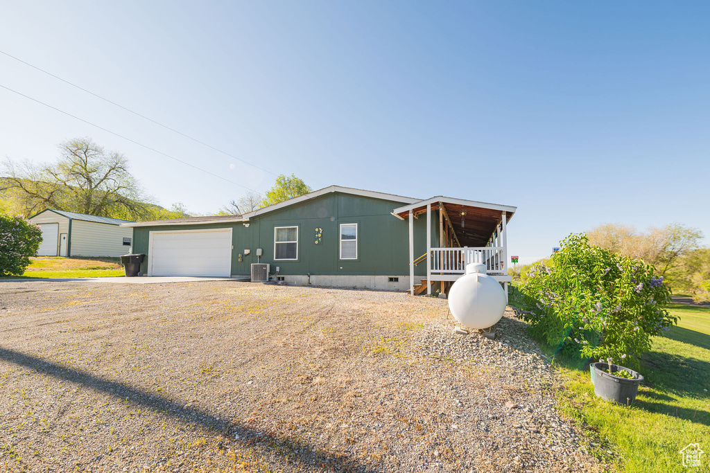 View of front of property with crawl space, a garage, driveway, cooling unit, and a front yard