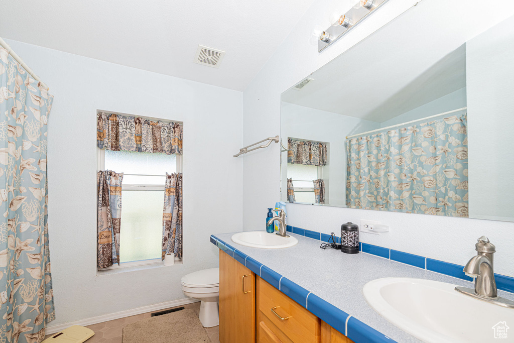 Full bathroom featuring toilet, double vanity, and baseboards