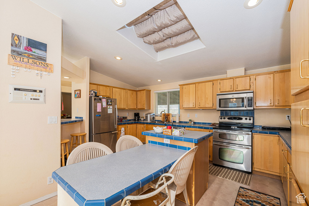 Kitchen with stainless steel appliances, lofted ceiling, a center island, recessed lighting, and a sink