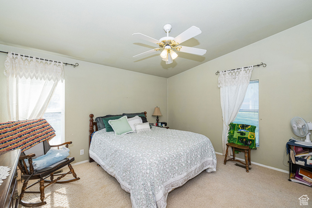 Bedroom featuring light colored carpet, baseboards, ceiling fan, and lofted ceiling