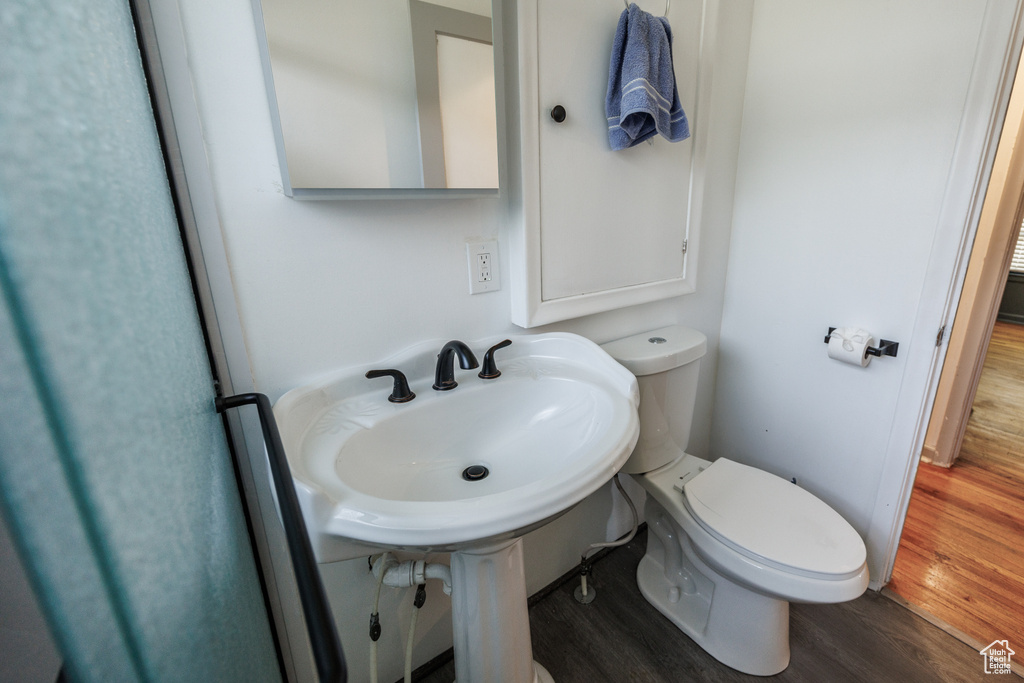 Half bathroom with wood finished floors and toilet