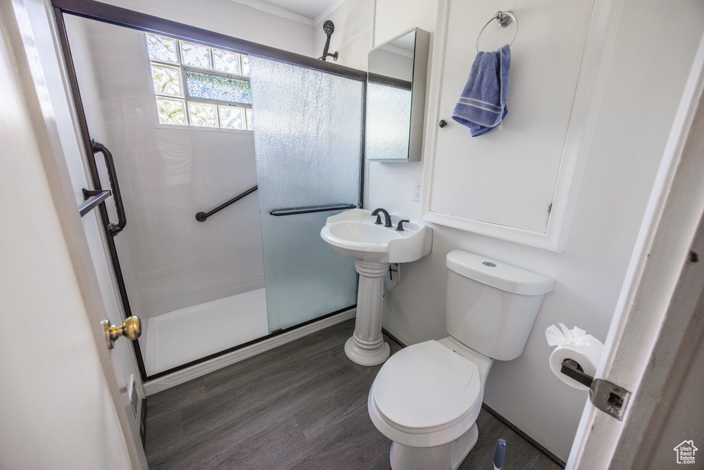 Bathroom with a stall shower, toilet, and wood finished floors
