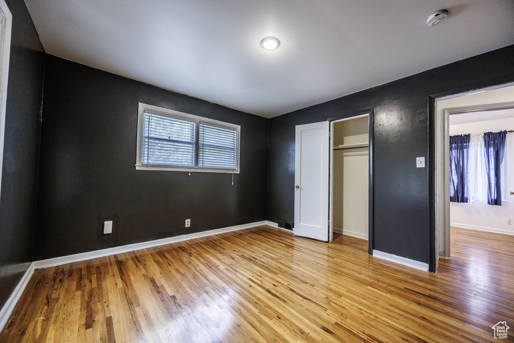 Unfurnished bedroom with light wood-style floors, baseboards, and a closet