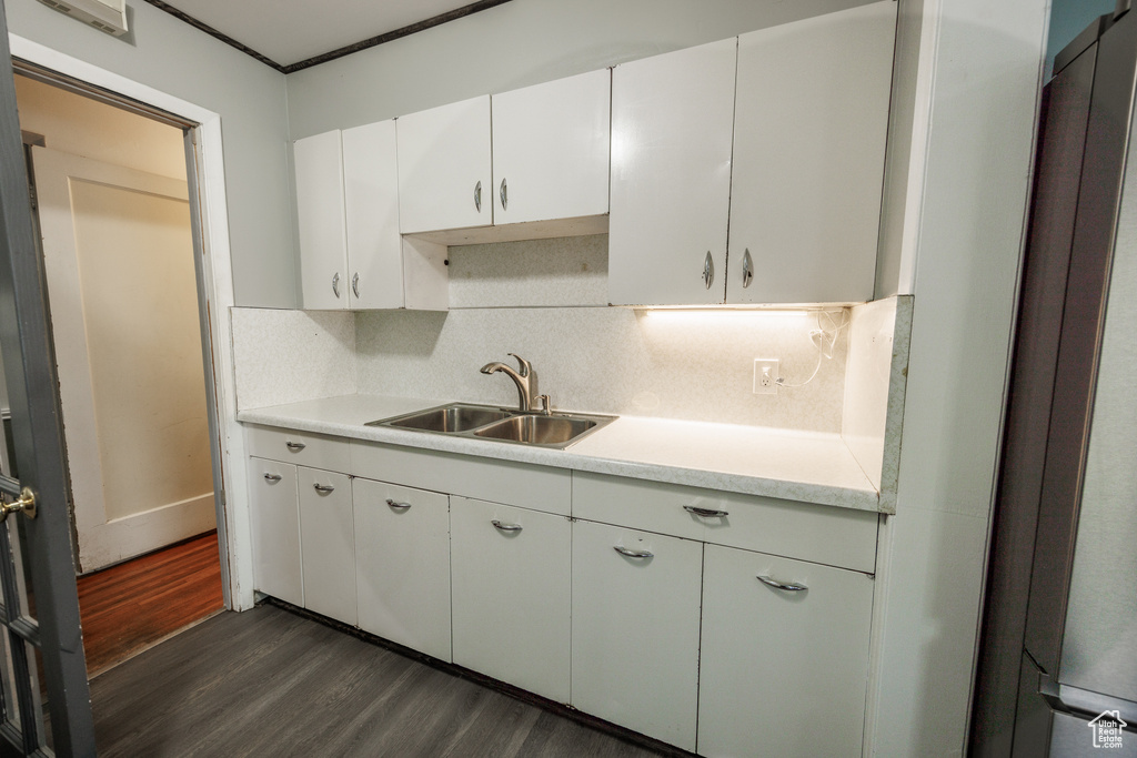 Kitchen featuring a sink, dark wood finished floors, light countertops, and decorative backsplash