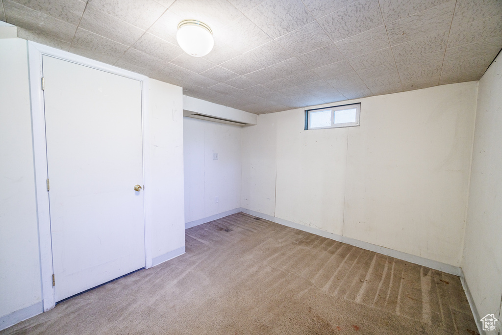 Basement featuring light colored carpet and baseboards