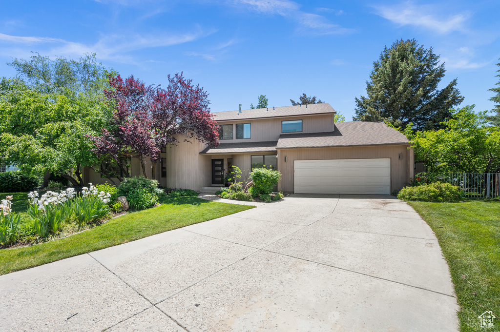 View of front of home with an attached garage, concrete driveway, and a shingled roof