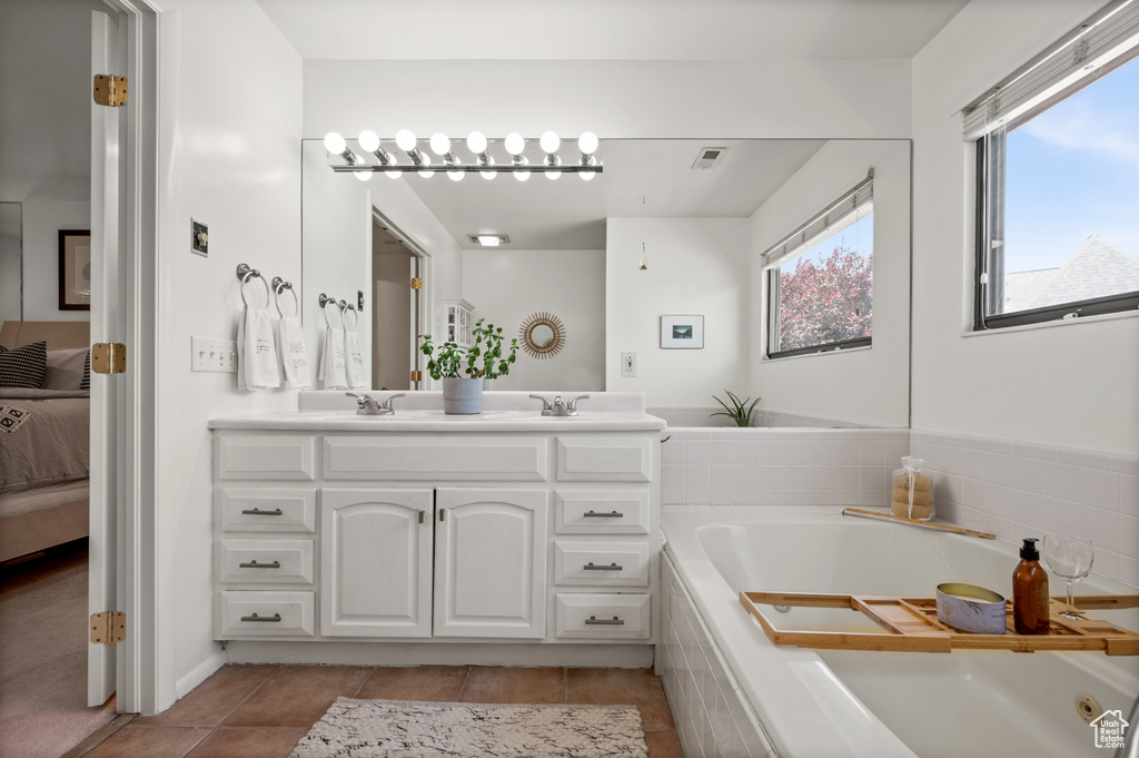 Full bathroom featuring connected bathroom, double vanity, a bath, and tile patterned flooring