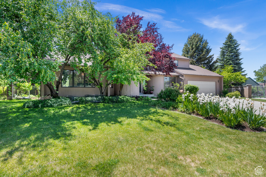 View of property hidden behind natural elements with a garage