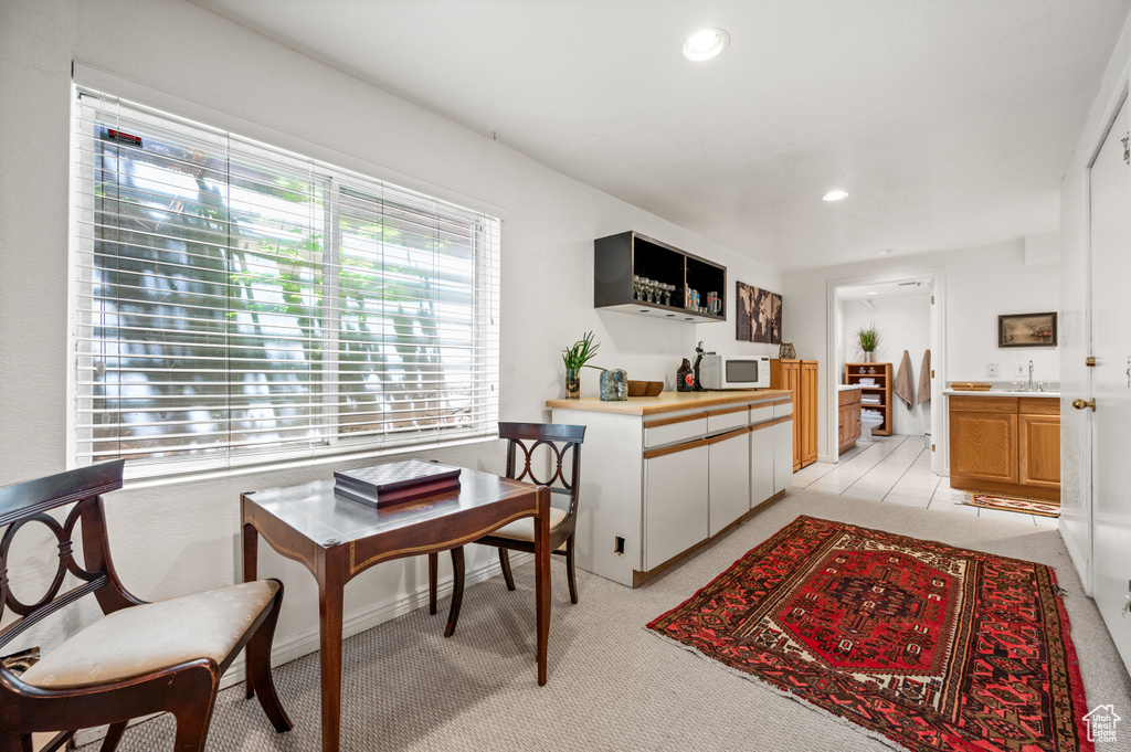 Kitchen with white microwave, recessed lighting, light carpet, light countertops, and a sink