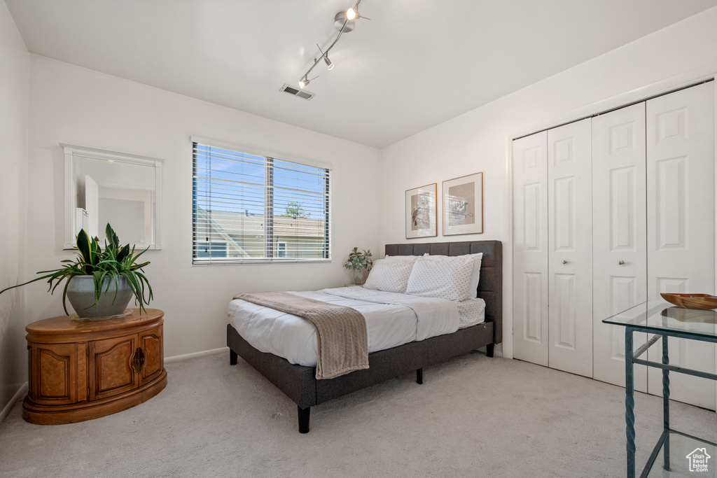 Bedroom with light colored carpet and a closet