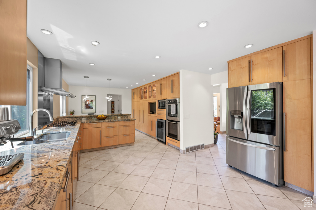 Kitchen featuring appliances with stainless steel finishes, a sink, a peninsula, light stone counters, and wine cooler