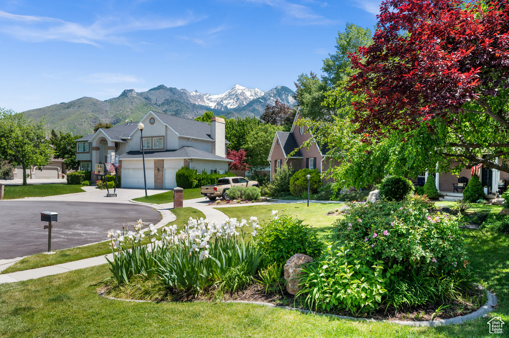 View of grassy yard with a mountain view, concrete driveway, and an attached garage