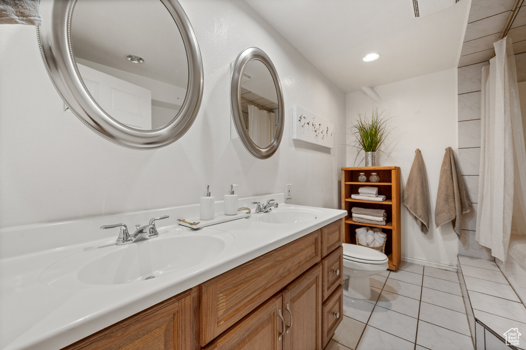 Bathroom featuring toilet, double vanity, and tile patterned floors