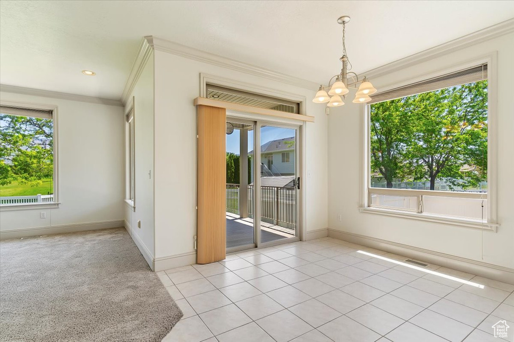 Spare room with a chandelier, crown molding, light tile patterned flooring, and baseboards
