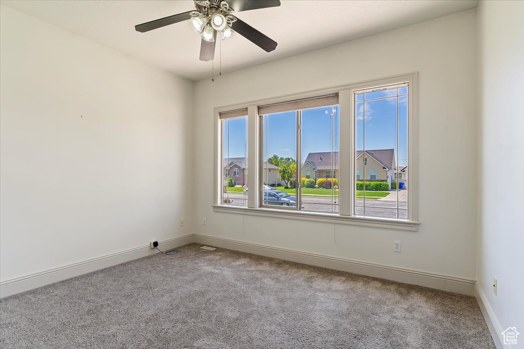 Carpeted spare room with baseboards and a ceiling fan