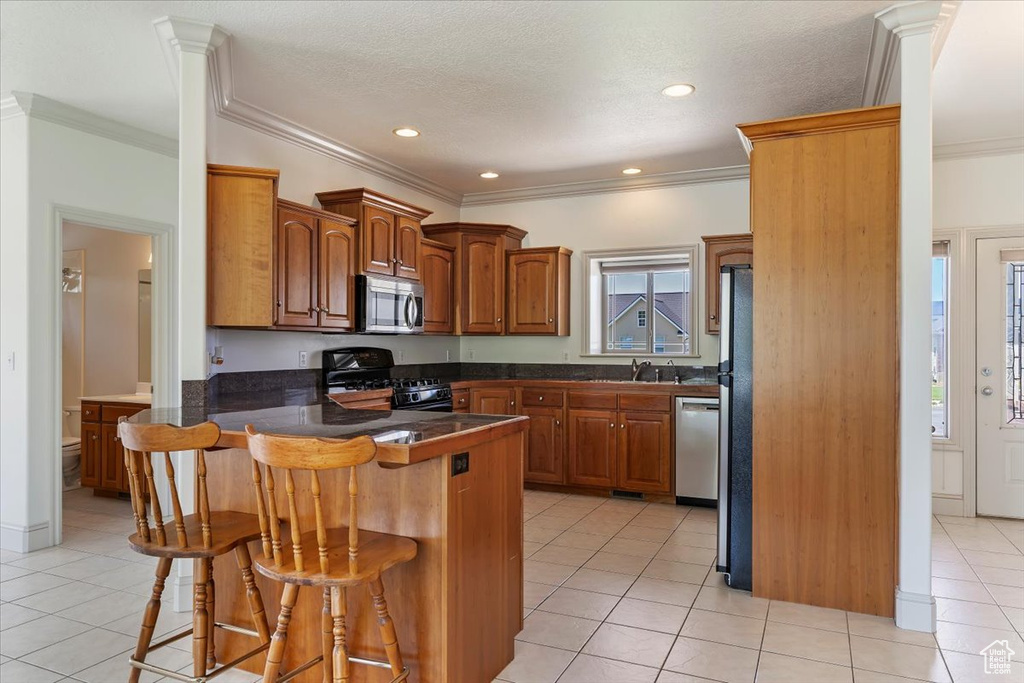Kitchen with appliances with stainless steel finishes, a peninsula, a breakfast bar, a sink, and light tile patterned flooring