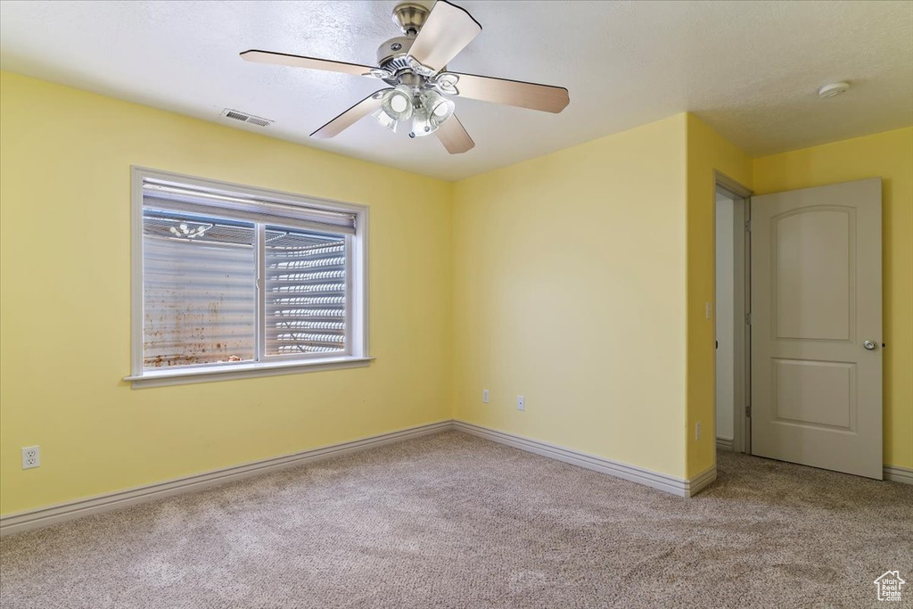 Spare room featuring carpet floors, ceiling fan, a smoke detector, and baseboards