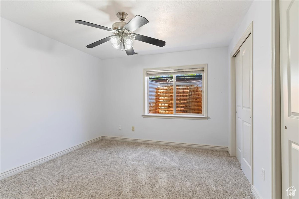 Unfurnished bedroom featuring carpet flooring, a closet, baseboards, and ceiling fan