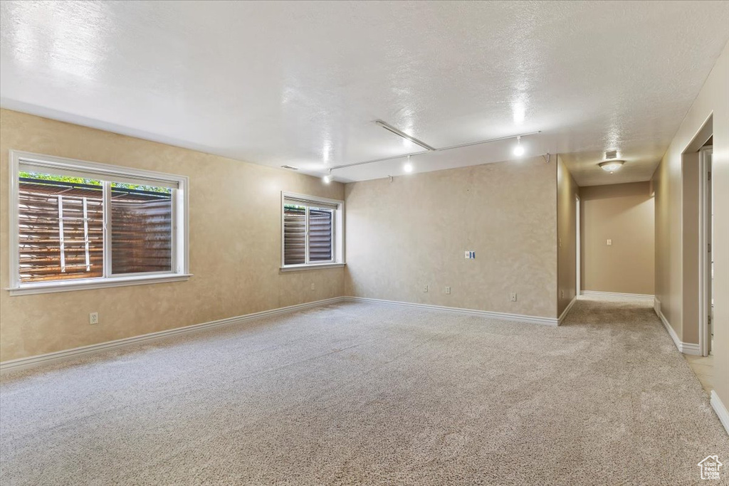 Spare room with rail lighting, light carpet, and a textured ceiling