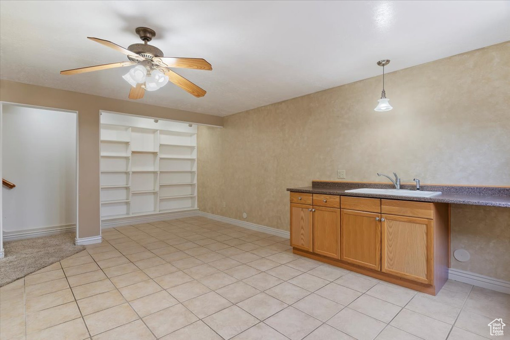 Kitchen with a sink, a ceiling fan, built in features, baseboards, and dark countertops