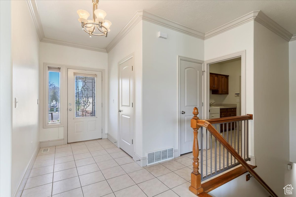 Foyer featuring a chandelier, crown molding, baseboards, and light tile patterned floors