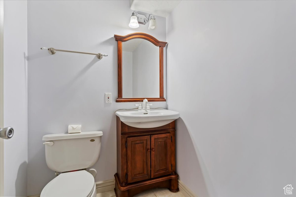 Bathroom with toilet, vanity, and baseboards