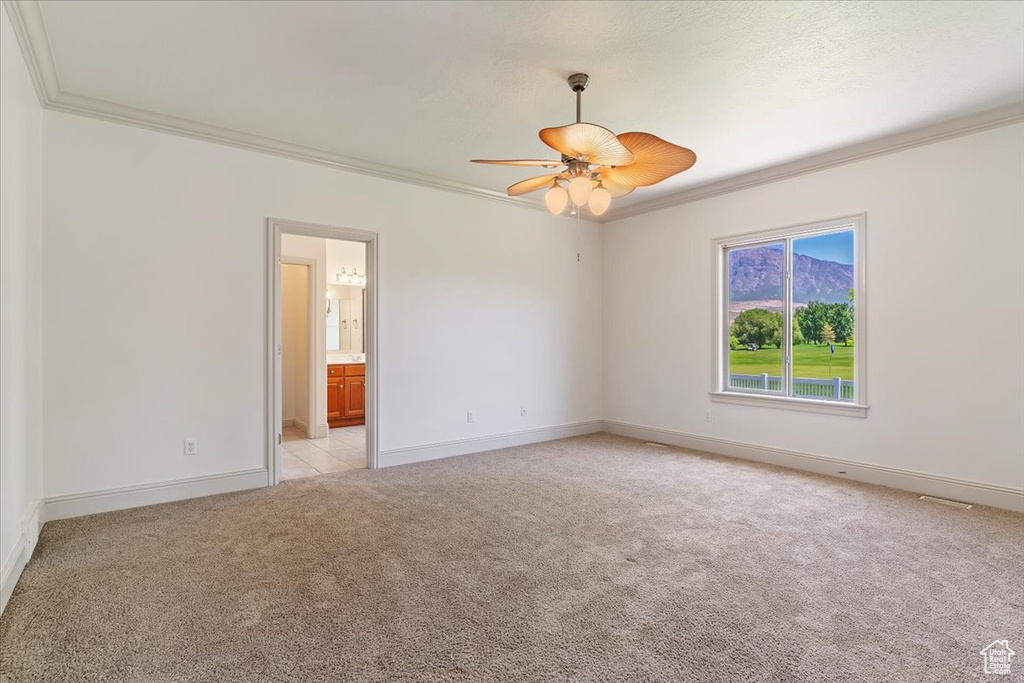 Unfurnished room with ornamental molding, light carpet, baseboards, and a ceiling fan
