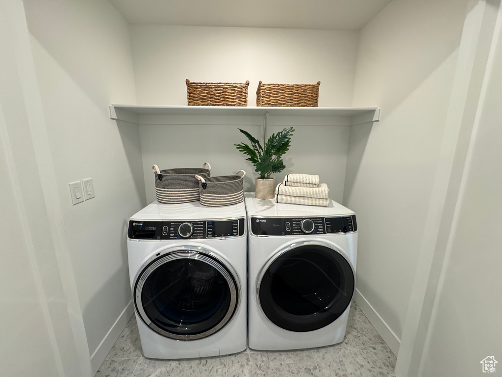 Laundry room with washer and clothes dryer and baseboards