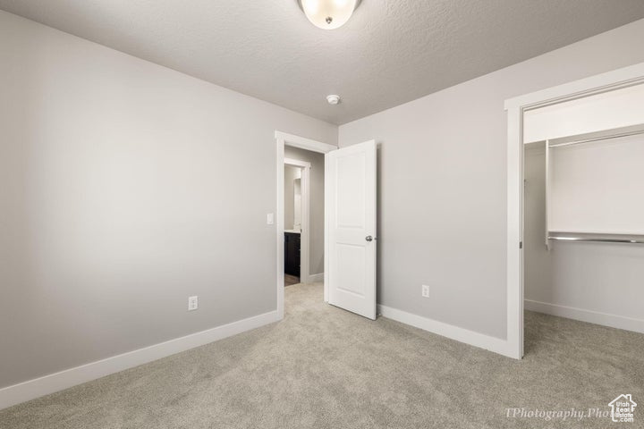 Unfurnished bedroom featuring carpet flooring, baseboards, a closet, and a walk in closet