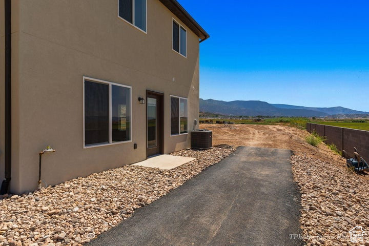 View of property exterior with a mountain view, stucco siding, central air condition unit, and a patio area