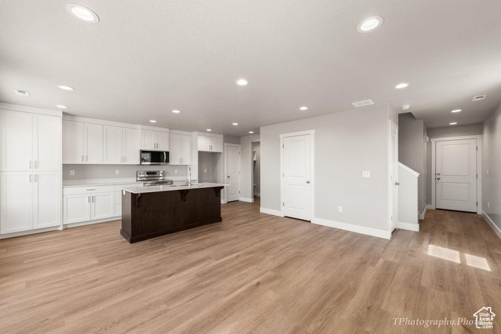 Kitchen featuring appliances with stainless steel finishes, recessed lighting, white cabinets, light wood finished floors, and light countertops