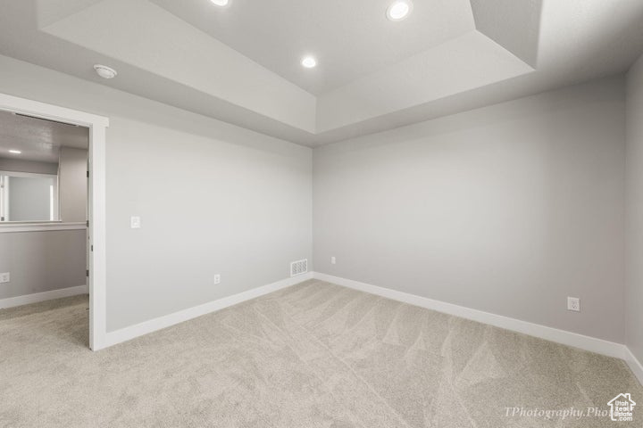 Carpeted empty room featuring a tray ceiling, recessed lighting, baseboards, and a smoke detector