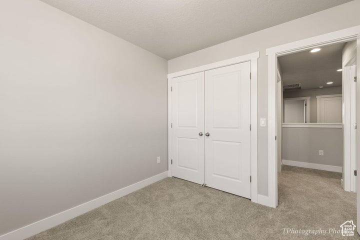 Unfurnished bedroom with light colored carpet, baseboards, a closet, and recessed lighting