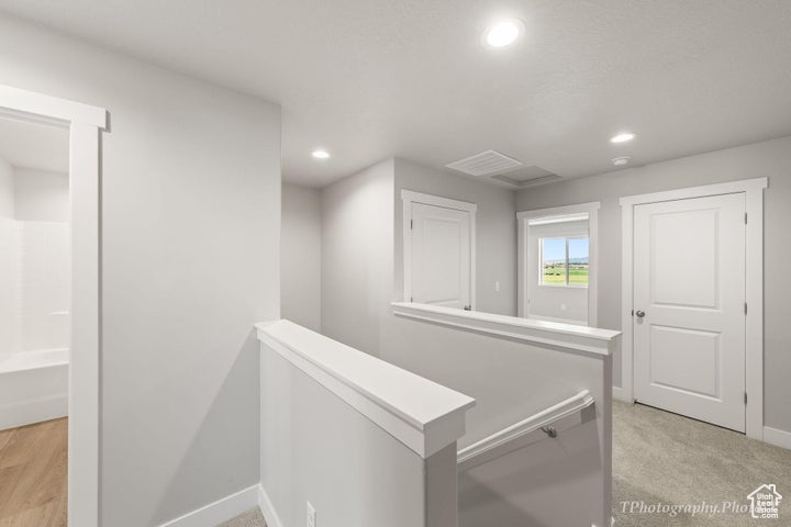 Hallway featuring an upstairs landing, baseboards, recessed lighting, and light colored carpet