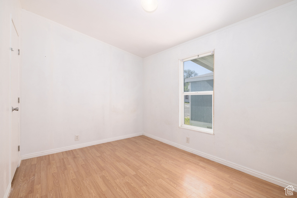 Spare room with light wood-style floors, baseboards, and ornamental molding