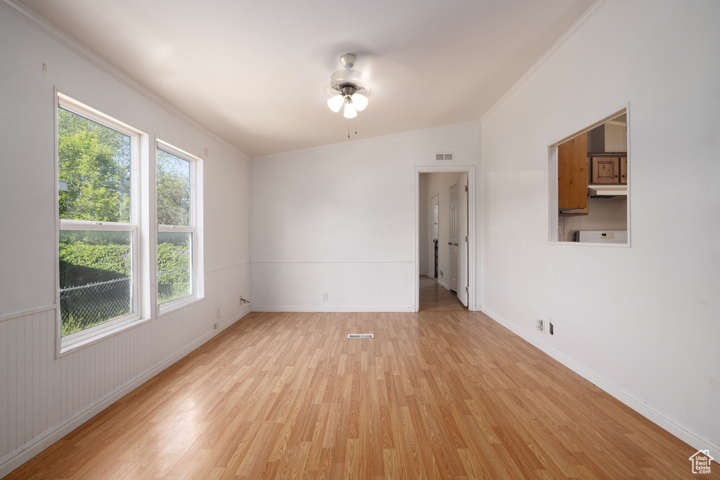 Spare room with light wood finished floors, ceiling fan, crown molding, and baseboards