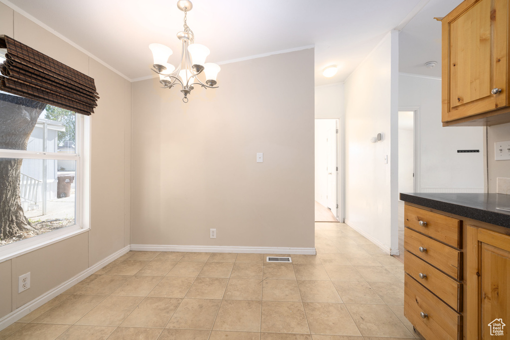 Unfurnished dining area featuring a chandelier, crown molding, light tile patterned floors, and baseboards