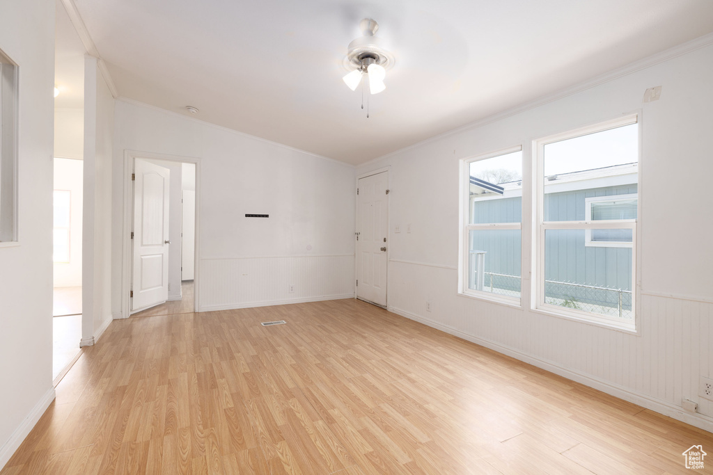 Empty room featuring light wood finished floors, a ceiling fan, and baseboards