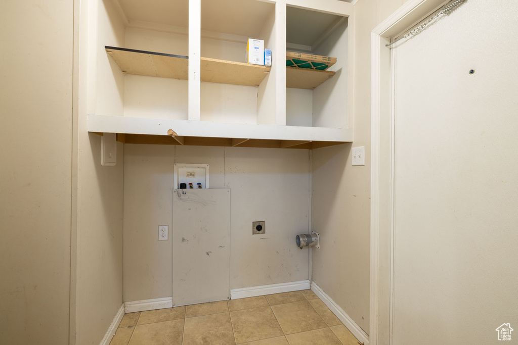 Laundry area featuring electric dryer hookup, hookup for a washing machine, light tile patterned floors, and baseboards