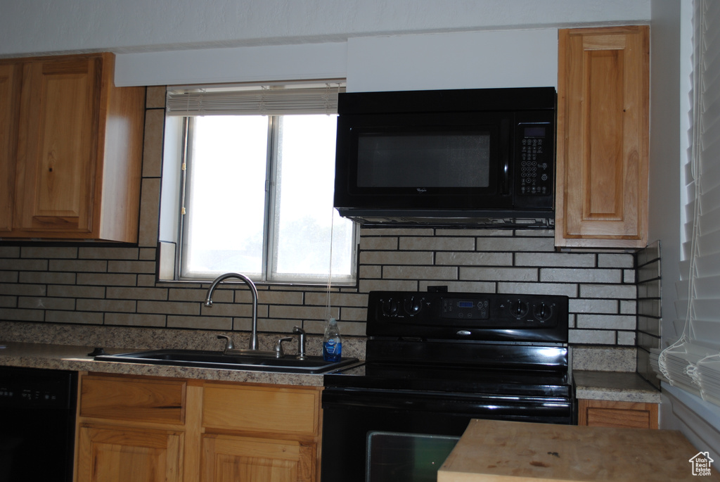 Kitchen featuring black appliances, a sink, and backsplash