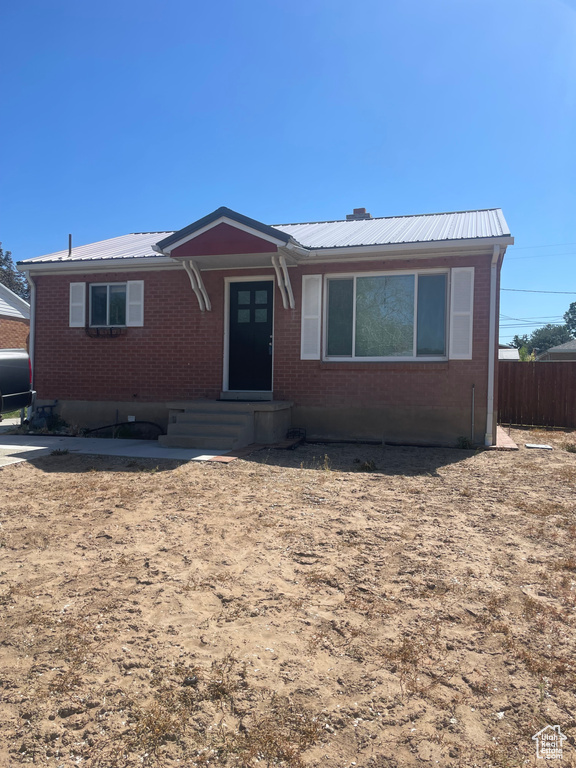 Ranch-style home with metal roof, brick siding, oil tank, and entry steps