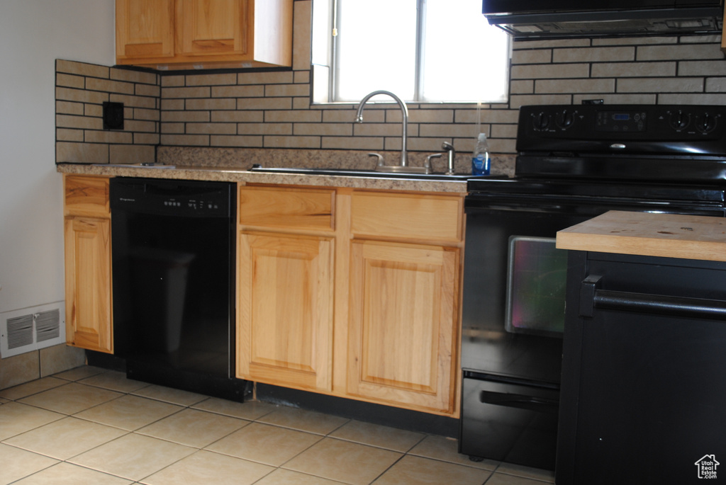 Kitchen featuring black appliances, a sink, light brown cabinetry, and light tile patterned floors