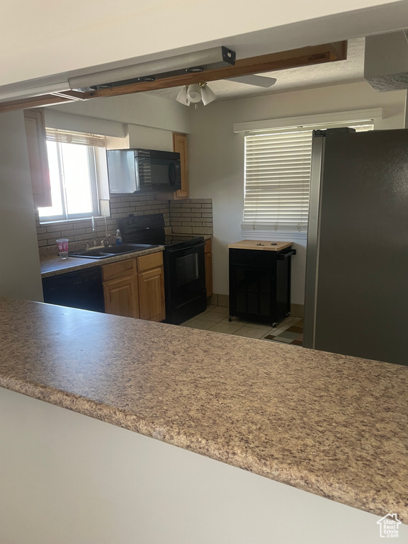 Kitchen with black appliances, backsplash, light tile patterned flooring, a sink, and a ceiling fan